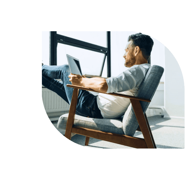 In seinem Stuhl kippelnder Mann am Laptop.